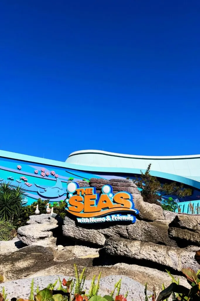 Vertical photo of the ride entrance to The Seas with Nemo & Friends with a bright blue sky behind it.